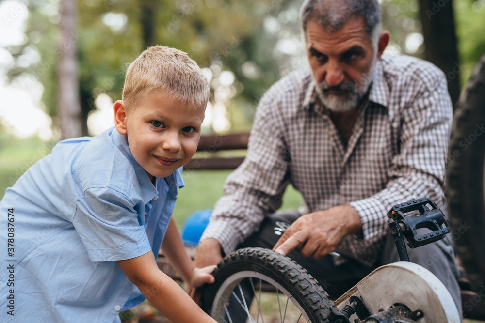 grandfather with his grandson at the city park fixing bicycle grandfather with his grandson at the city park fixing bicycle