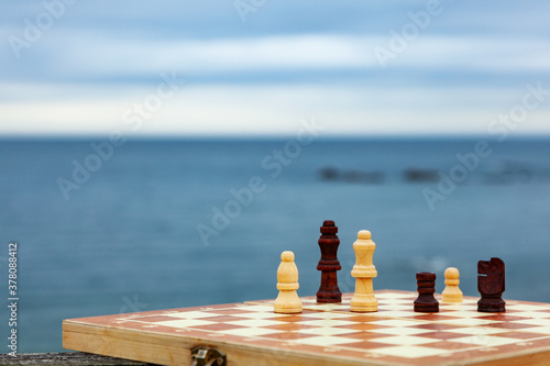 Playing chess on a Board on the beach. Chessboard on the background of the sea on a Sunny day. Vacation on the coast.