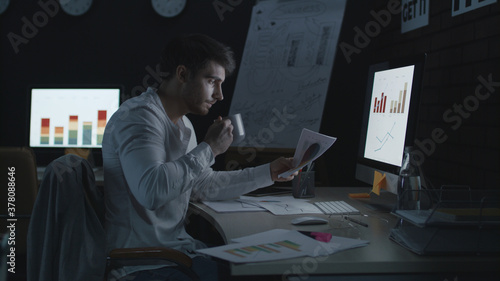 Serious businessman working on computer in night office.