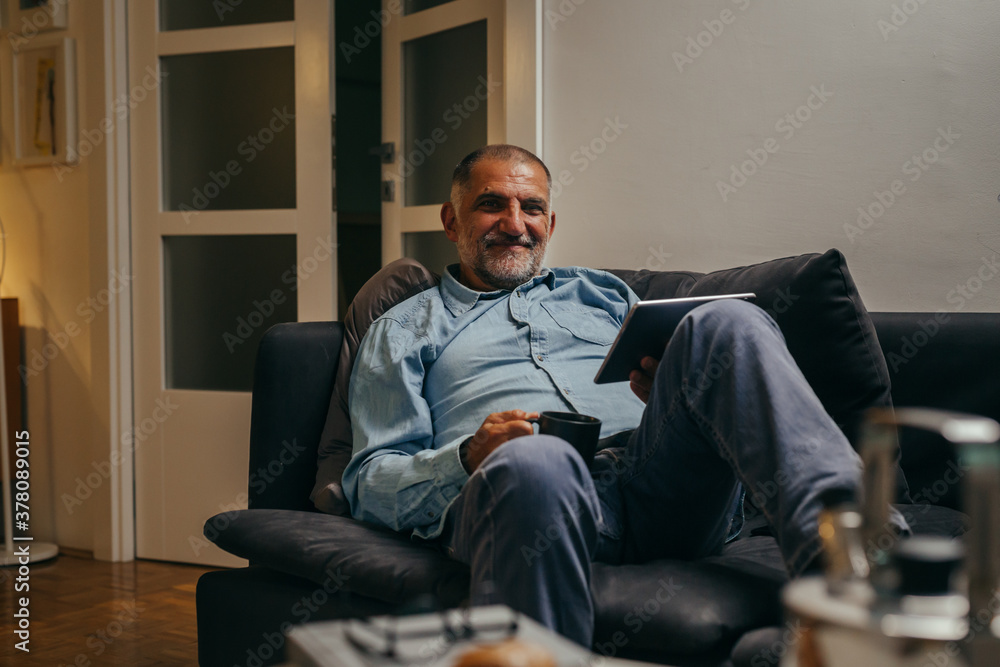 middle aged man sitting sofa using tablet computer at home middle aged man sitting sofa using tablet computer at home
