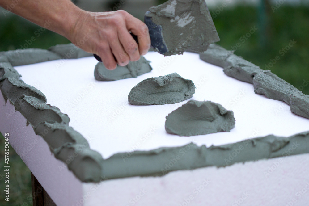 Wall insulation with polystyrene panels, glue application and installation.