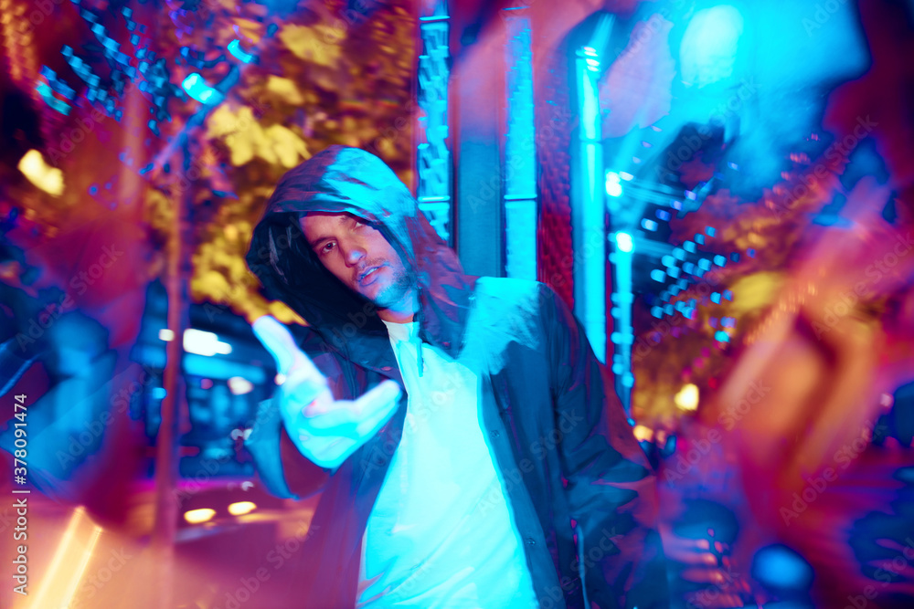 Moody and proud. Cinematic portrait of stylish young man in neon lighted room. Bright neoned colors. Caucasian model, musician outdoors. Youth culture in party, festival style and music concept.