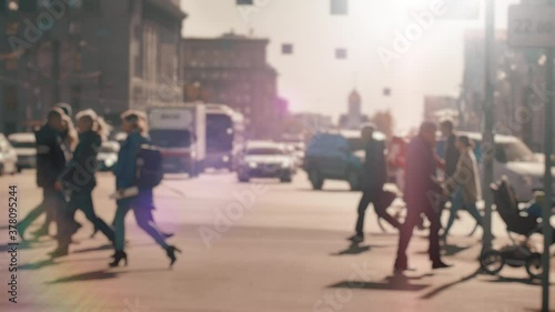 Lens blur, out of focus. A crowd of pedestrians is walking along the street against the background of passing cars. People walk around the big city. City life. Slow motion