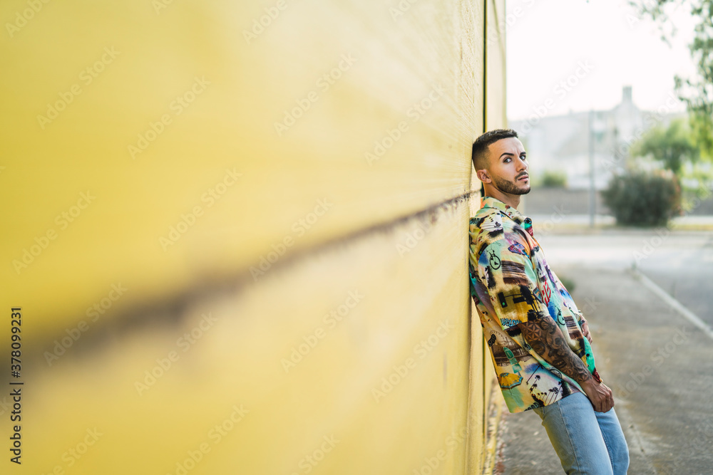 Chico atractivo joven posando delante de pared amarilla con estilo vintage