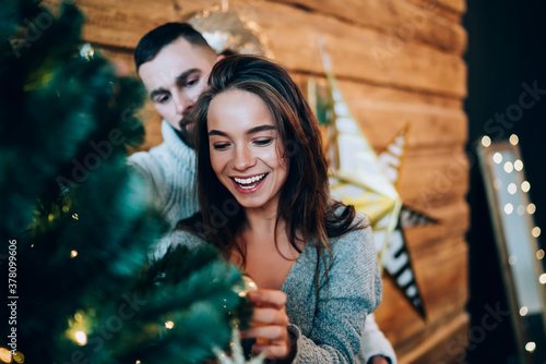 Glad couple decorating Christmas tree