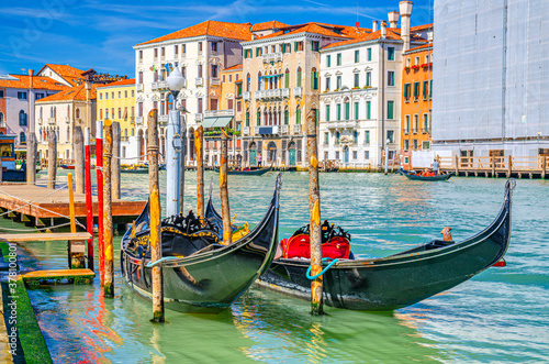 Gondolas traditional boats moored in wooden pier dock of Grand Canal waterway in Venice historical city centre with row of colorful buildings Venetian architecture. Veneto Region, Northern Italy.