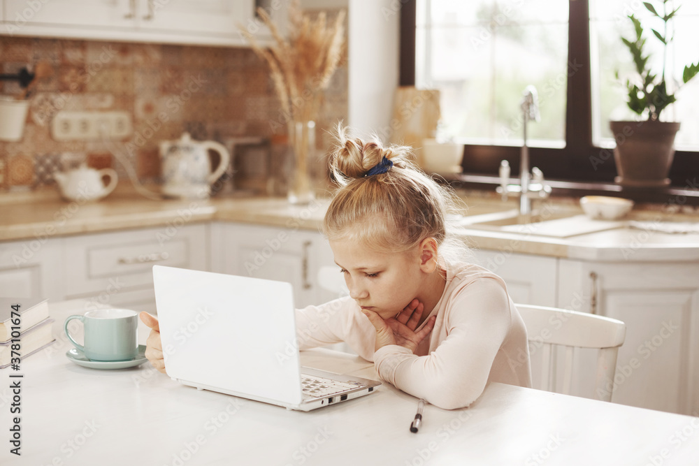 Teenage girl watching video tutorial on laptop in kitchen, distance learning, online education, home learning concept Teenage girl watching video tutorial on laptop in kitchen, distance learning, online education, home learning concept