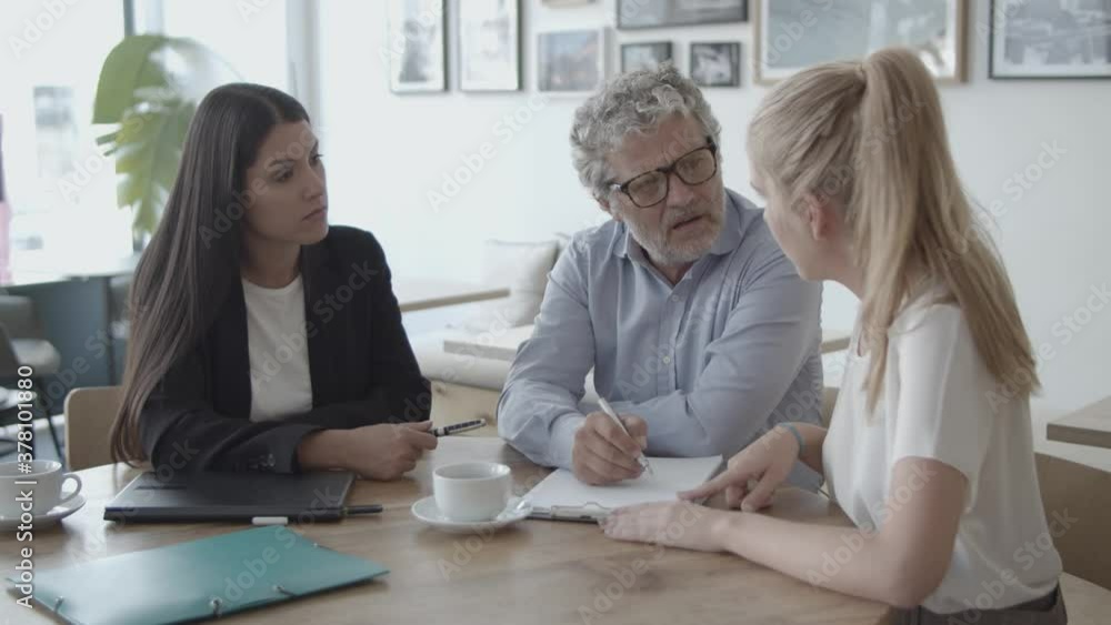 Consultant helping clients to filling in application, talking to customers, explaining paper details. Consulting and paperwork concept Consultant helping clients to filling in application, talking to customers, explaining paper details. Consulting and paperwork concept