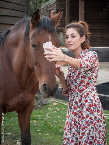 Vertical shot of female taking a selfie with andalusian horse. © Daniel