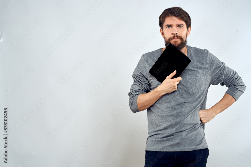 A man in a gray sweater a tablet in the hands of emotions Internet technology lifestyle light background A man in a gray sweater a tablet in the hands of emotions Internet technology lifestyle light background