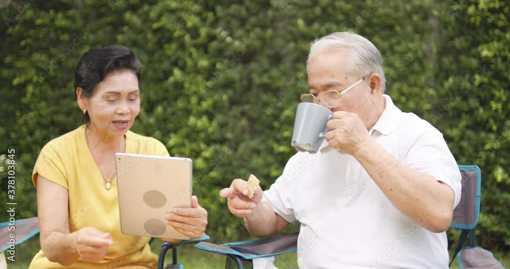 Slow motion of happy old woman sitting on the chair and pointing at tablet to her husband. Glad man is resting with coffee in garden.
Slow motion of happy old woman sitting on the chair and pointing at tablet to her husband. Glad man is resting with coffee in garden.