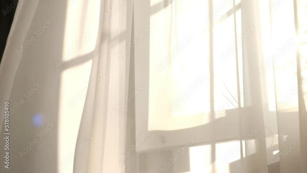 wind blows through the open window in the room. Waving white tulle near the window. sun's rays shine through the transparent tulle wind blows through the open window in the room. Waving white tulle near the window. sun's rays shine through the transparent tulle