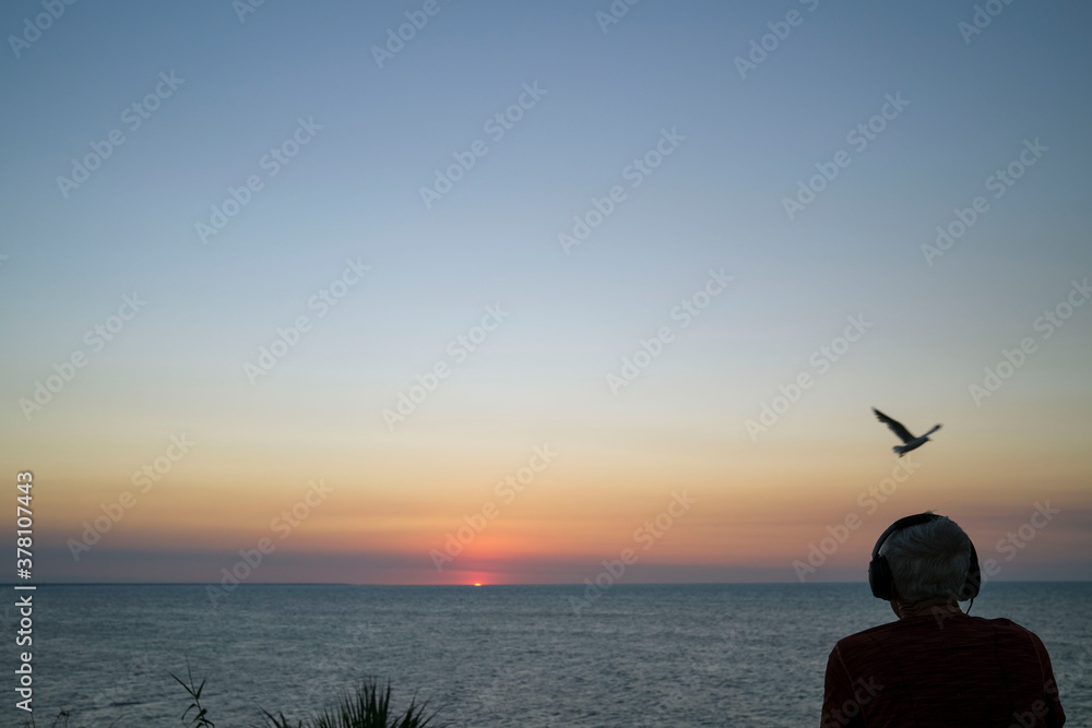 Silhouette of a man wearing headphone and watching the sunset