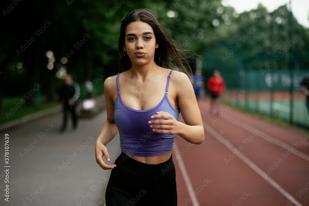 Beautiful woman training on running track. Young woman in blue sportswear listening the music. Beautiful woman training on running track. Young woman in blue sportswear listening the music.
