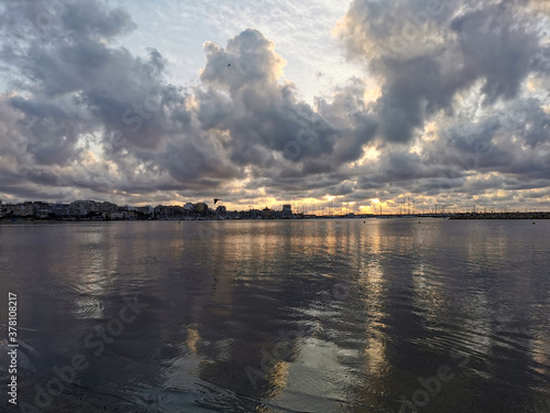 the reflex of dark storm clouds on the surface of the sea and the silhouette of the port on the horizon