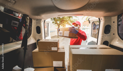 Photos Courier man wearing face mask while unloading delivering packages from a truck d