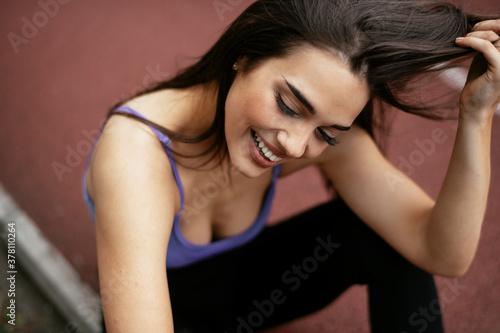 Beautiful woman sitting on running track. Young woman in blue sportswear...