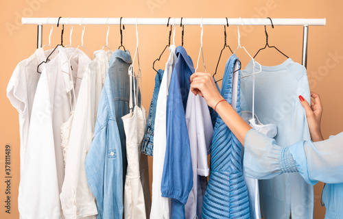 Unrecognizable woman choosing clothes standing near rack