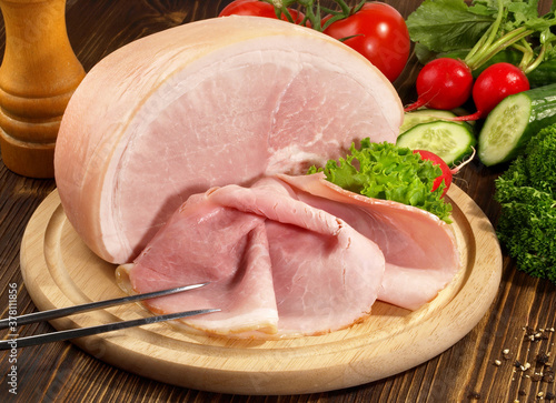 Принти на полотні Cooked Ham with Ham Slices on a wooden Plate