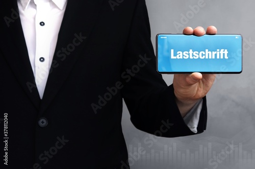 Lastschrift. Mann zeigt Telefon (Handy) mit Wort im Display. Weißer Text auf blau. photo