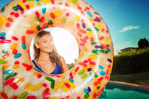 Happy beautiful smiling girl portrait in inflatable buoy doughnut near swimming pool