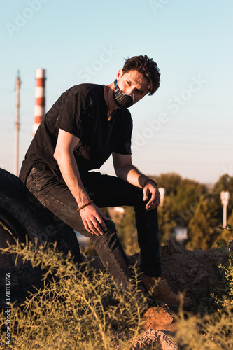 A physically distant and socially connected young man in a black outfit in an industrial zone