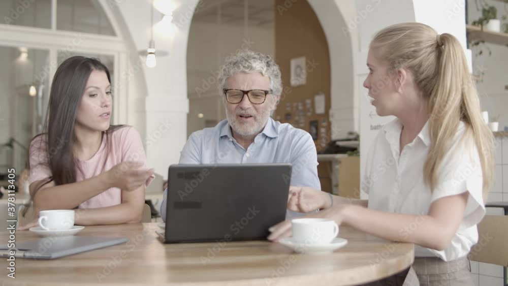Successful businesswomen showing data via laptop and explaining. Concentrated CEO in glasses and brunette manager listening colleague, talking and sitting at table. Business and teamwork concept Successful businesswomen showing data via laptop and explaining. Concentrated CEO in glasses and brunette manager listening colleague, talking and sitting at table. Business and teamwork concept