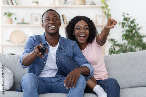 Emotional african man and woman watching TV at home