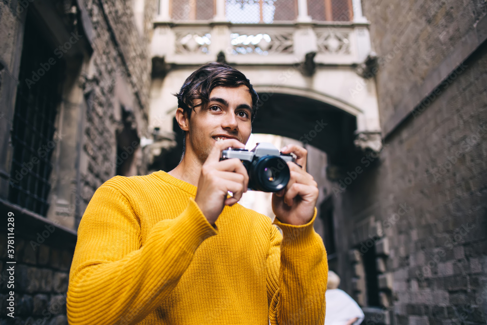 Cheerful caucasian male traveler enjoying visiting town making picture on camera exploring historic places, smiling man tourist taking photo satisfied with spending vacation free time on hobby