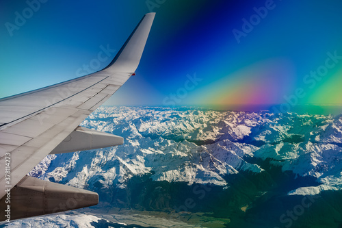 Fotografie Flying in to Queenstown New Zealand with the aircraft wing on the left, views of snow capped mountains and the rainbow glare from a polarizing filter against the aircraft window