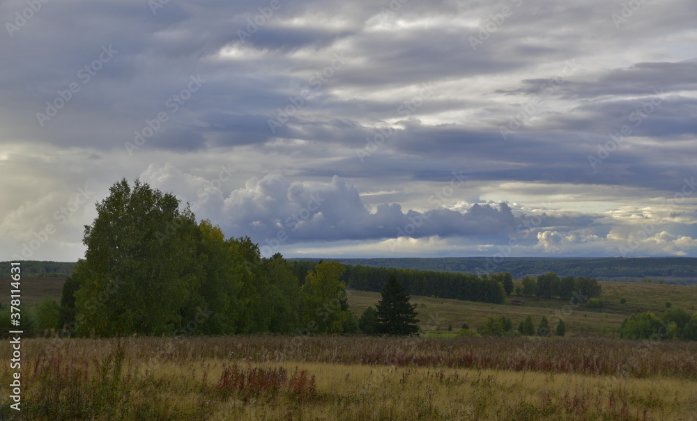 September panorama of collective farm fields and copses. Autumn bad weather in the foothills of the Western Urals.
