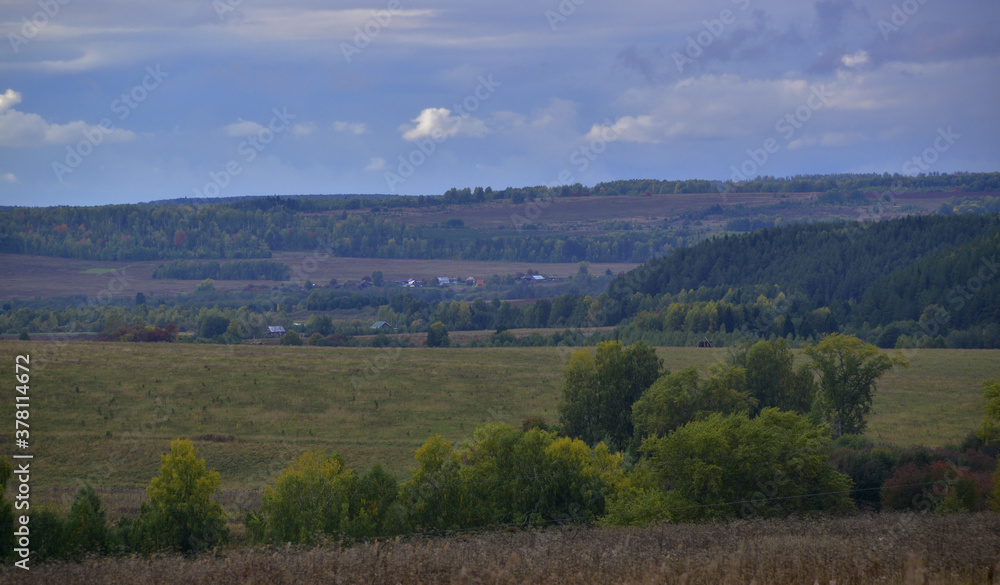 Heavy rain clouds over village fields and copses. Autumn bad weather in the foothills of the Western Urals.
