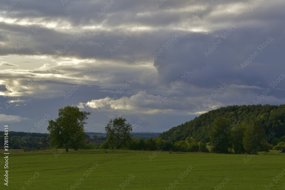 Heavy rain clouds over the village field and mountains overgrown with coniferous forest. Autumn bad weather in the foothills of the Western Urals. Heavy rain clouds over the village field and mountains overgrown with coniferous forest. Autumn bad weather in the foothills of the Western Urals.