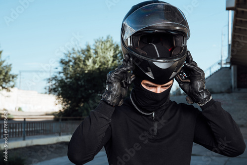 A handsome biker fastens his helmet. Putting on the helmet.