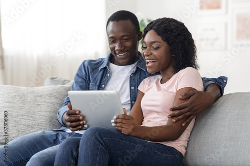 Smiling african man and woman websurfing together at home