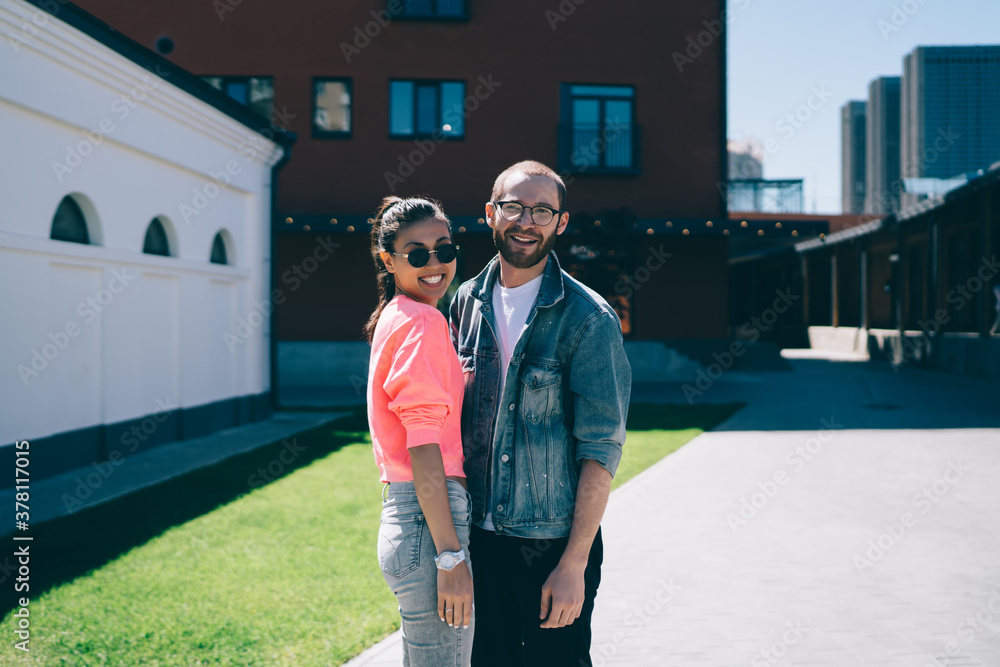 Portrait of happy man and woman in stylish glasses having relation date at urban setting enjoying day in city, cheerful millennial male and female in trendy apparel laughing while having fun outdoors