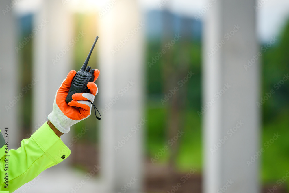 A close-up of a construction worker holding a radio communication for use of a construction radio. A close-up of a construction worker holding a radio communication for use of a construction radio.