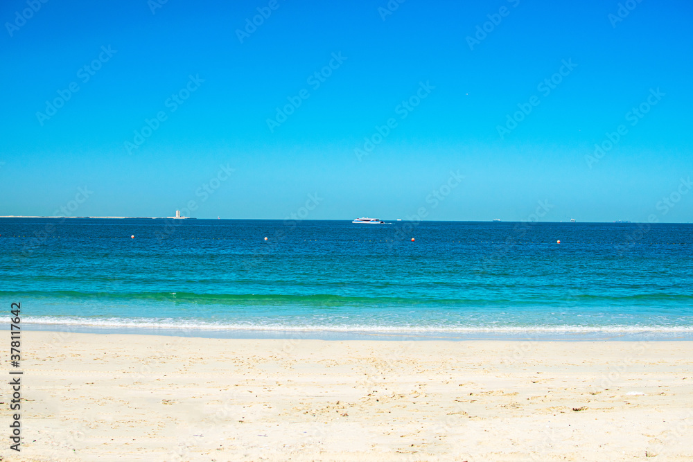 Beautiful public beach with turquoise water and a white sand in Persian Gulf shoreline, Dubai.