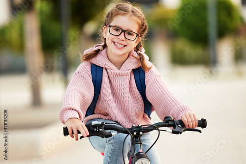 Funny girl goes to school on a bicycle.