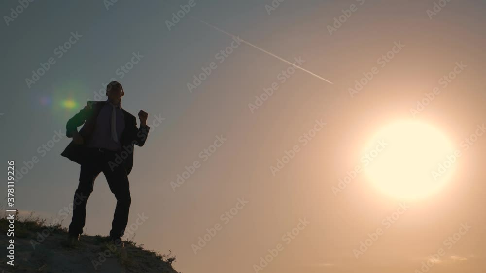 Business man entrepreneur jumps on top of a mountain at sunset, happy raising his hands to success, deal, career. The concept of teamwork. Business man entrepreneur jumps on top of a mountain at sunset, happy raising his hands to success, deal, career. The concept of teamwork.
