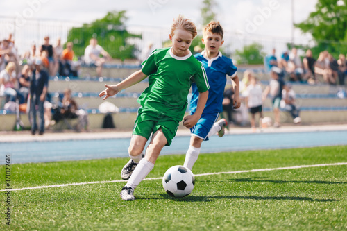 Young boys playing soccer game. Kids having fun in sport. Happy kids compete in football game. Running soccer players. Competition between players running and kicking football ball. Football school