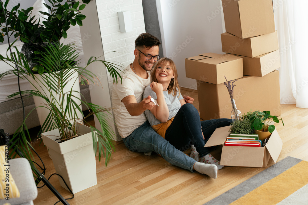 Husband and wife are moving into the apartment. Happy couple is unpacking their belongings.. Husband and wife are moving into the apartment. Happy couple is unpacking their belongings..