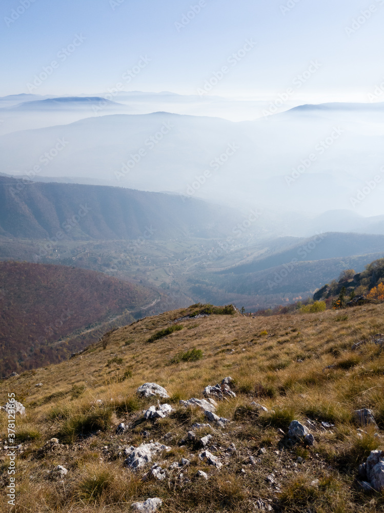 Fototapeta premium Scenic view from Vlašić mountain to the valley filled with fog and mountain peaks above the fog in autumn during a sunny day