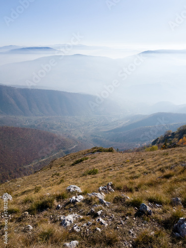 Scenic view from Vlašić mountain to the valley filled with fog and mountain peaks above the fog in autumn during a sunny day