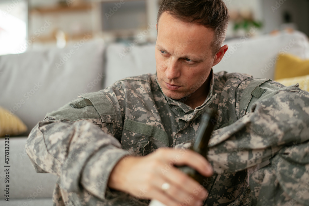 Depressed soldier with bottle sitting in livig room., Alcohol addiction... Depressed soldier with bottle sitting in livig room., Alcohol addiction...