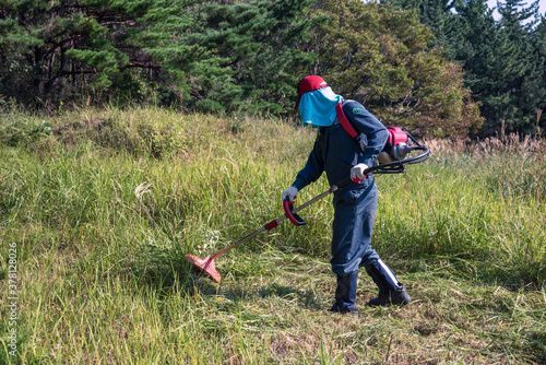 A person who removes weeds using a brush cutter.