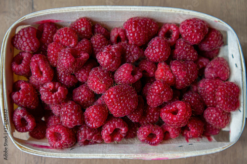 
Lots of ripe red raspberries in a white basket