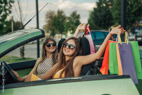 Portrait of beautiful pretty cheer girls going home after shopping sitting in the car glad with new stuff  hands raised above head wear yellow dotted dress black friday concept © Volodymyr