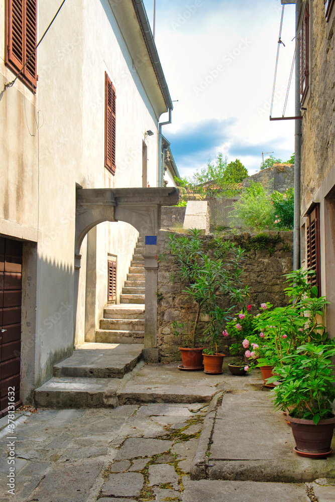 The town center with traditional historic houses, old narrow street and flower pots in the small Istrian city Buzet, Croatia