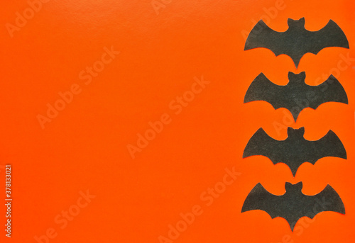 Black paper bats lie on an orange background.
